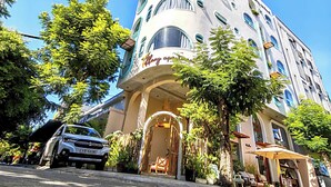 Un hôtel à plusieurs étages, doté d’une façade incurvée, d’une entrée couverte et d’un espace de stationnement où se trouve une voiture garée.