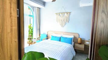 Ein Schlafzimmer mit einem Bett, einem Deckenventilator, einem Wandbehang aus Makramee und einem Fenster mit Vorhängen.