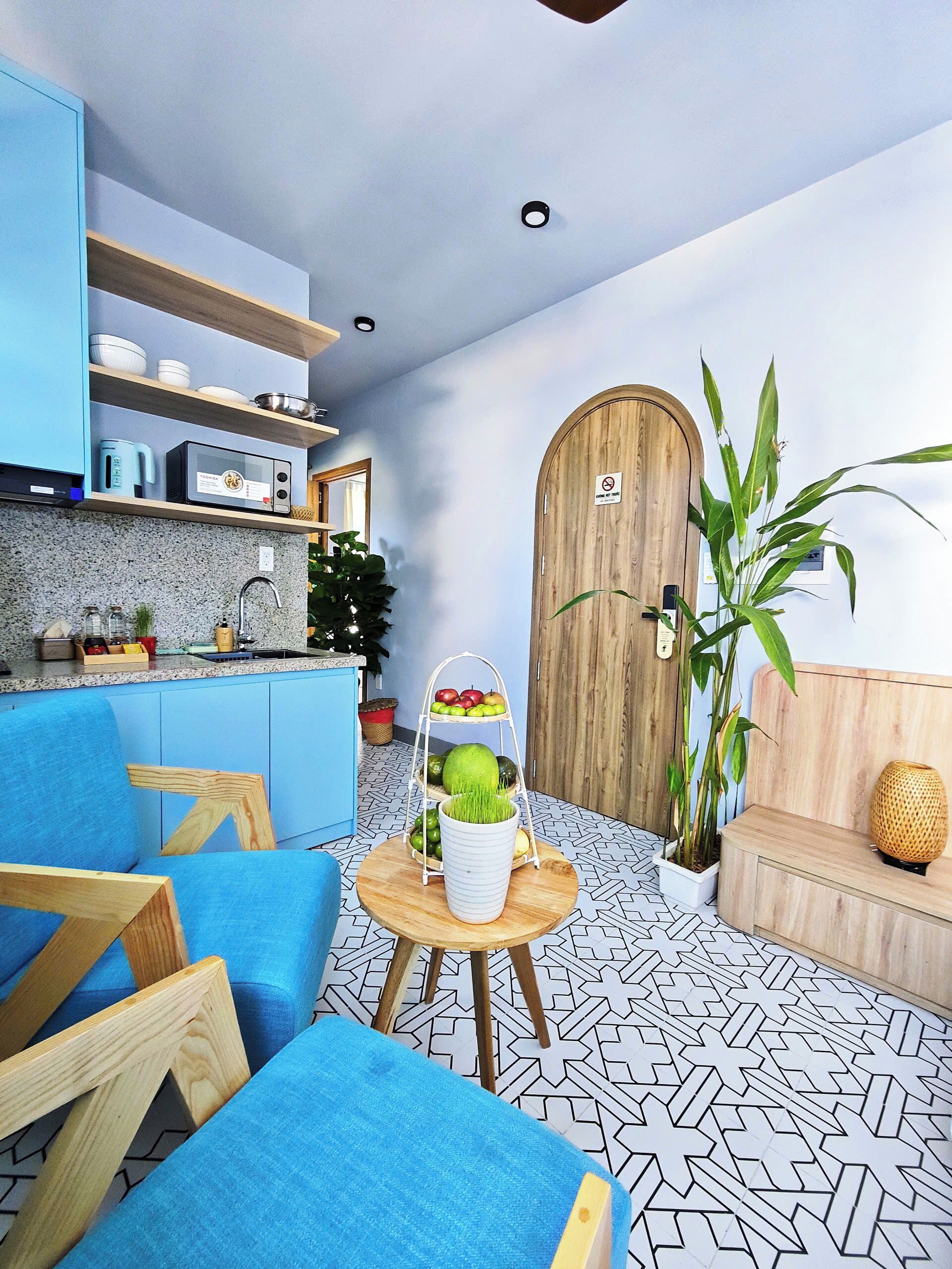 Una cocina moderna con armarios azules, una puerta de madera y un comedor con mobiliario azul.