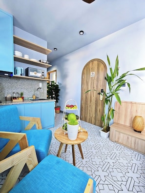 Cozinha moderna com armários azuis, porta de madeira e área de jantar com mobiliário azul.