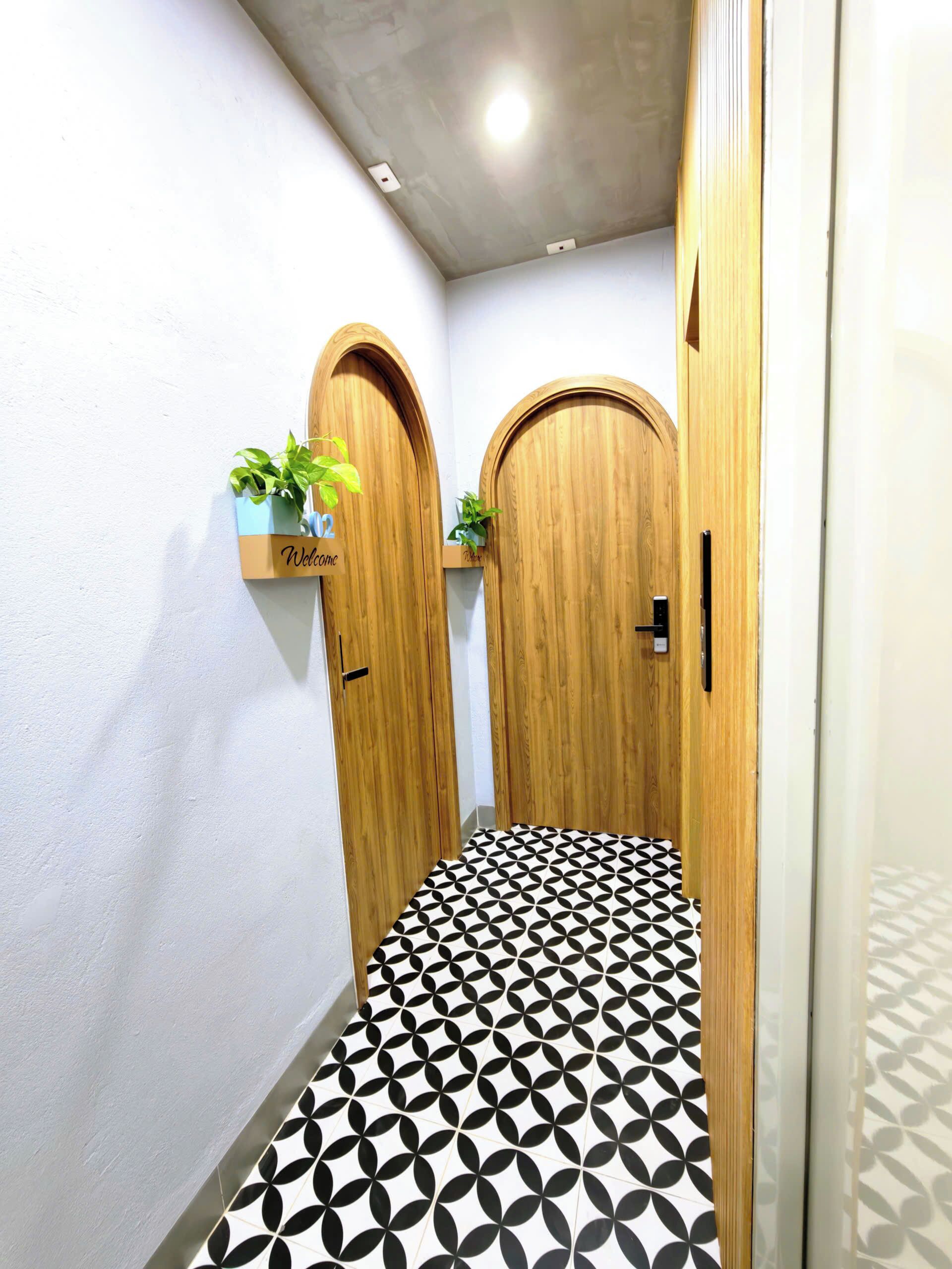 Un pasillo con dos puertas de madera, un letrero de bienvenida y un suelo estampado.