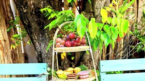 Une table en bois dressée pour un pique-nique, avec un panier de fruits, des boissons et une théière.