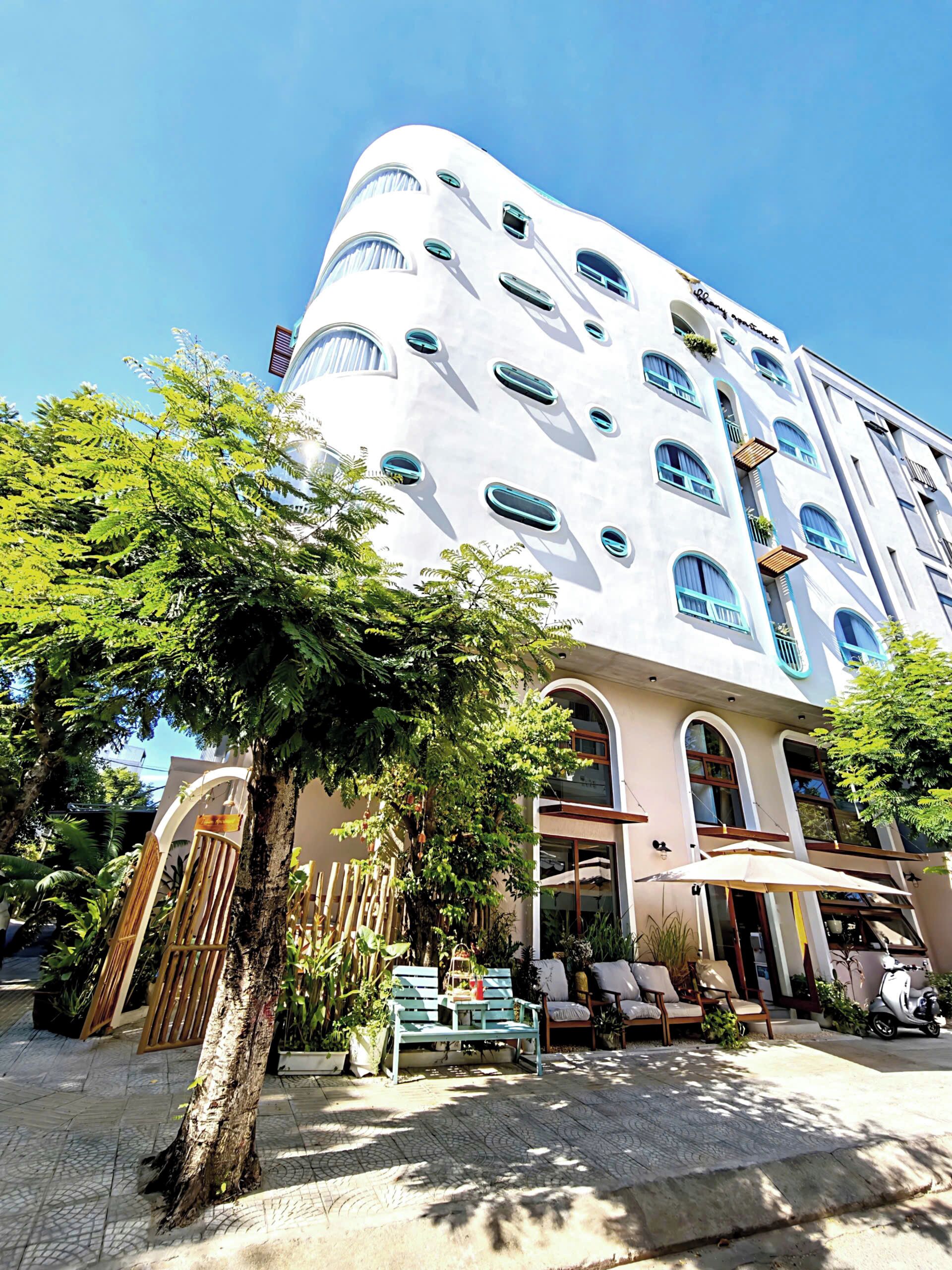 Un edificio moderno con varios balcones y un patio con mobiliario exterior.