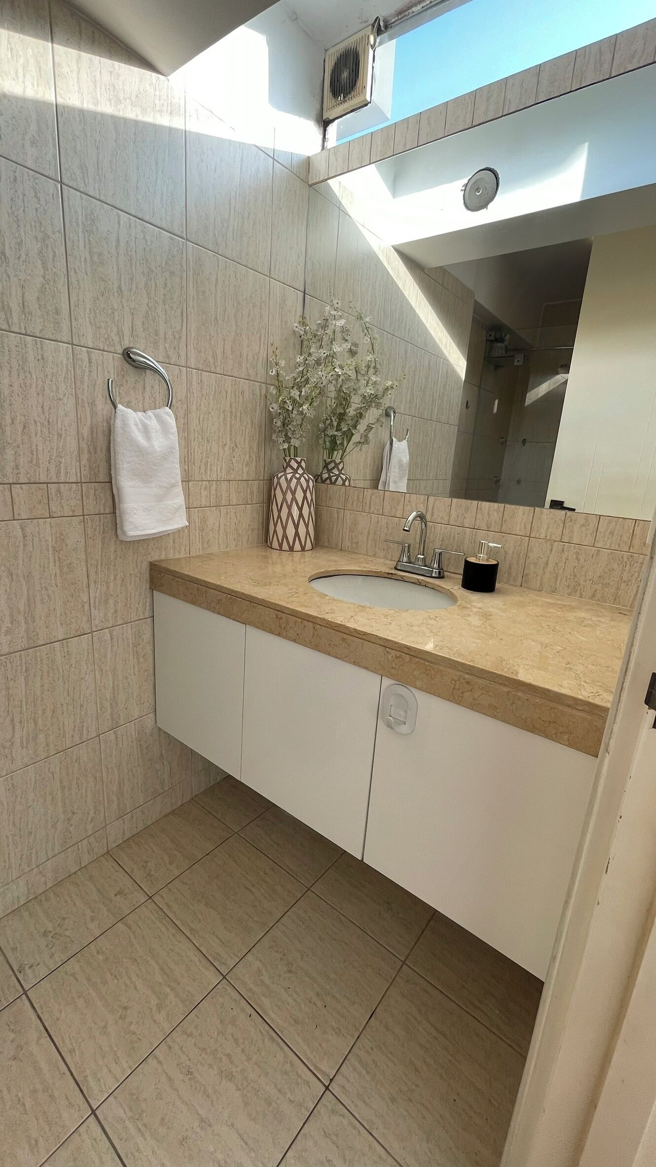 A bathroom with a sink, mirror, towel rack, and a decorative vase.