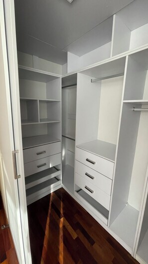 Un dressing accessible sans porte, doté d’étagères ouvertes, de tiroirs et d’un espace pour suspendre les vêtements.
