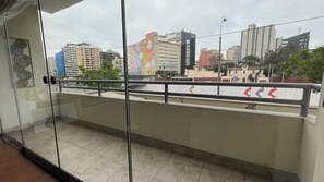 Ein Balkon mit Glasgeländer und Blick auf eine Stadtlandschaft mit verschiedenen Gebäuden.