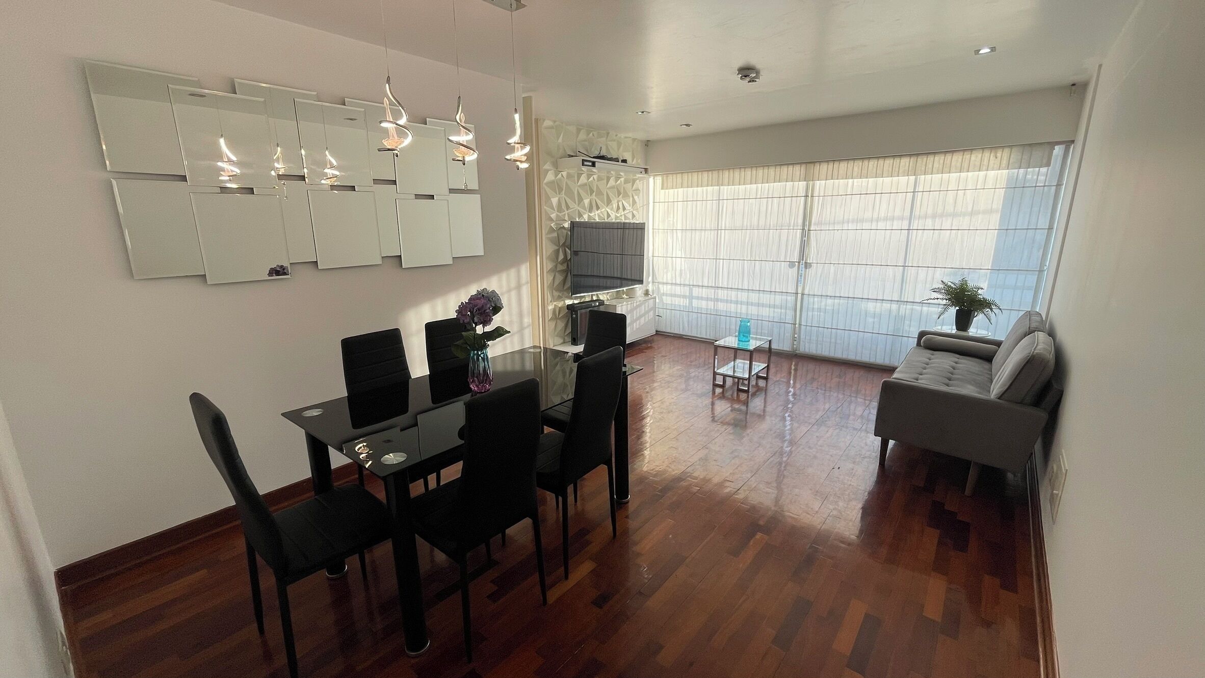 Una sala moderna con comedor, sofá y televisor.