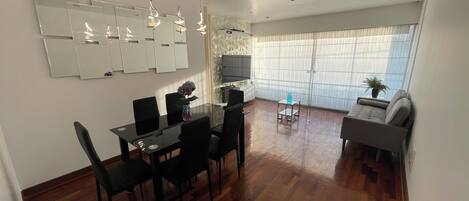 Una sala moderna con comedor, sofá y televisor.