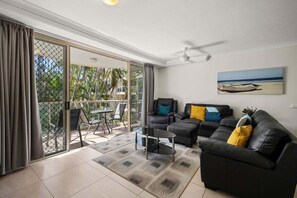 A living room with a sofa, a coffee table, and a painting on the wall. - Miami Beachside - 32 (Gold Coast)