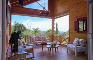 A wooden deck with a sofa, chairs, and a table, overlooking a scenic landscape.