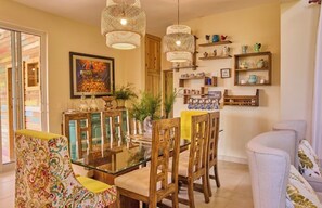 A dining area with a glass table, wooden chairs, and hanging wicker lamps. - Vrbo Property (Jarabacoa)