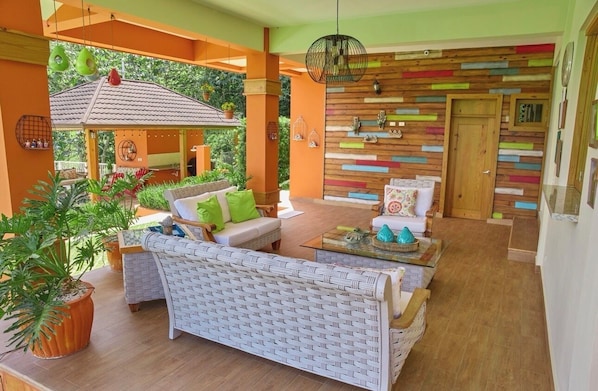 A cozy outdoor seating area with a wicker sofa, a small table, and potted plants.