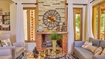 A living room with a fireplace, a round mirror, and a coffee table.