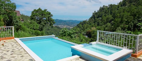 Ein rechteckiger Swimmingpool mit einer gefliesten Kante, umgeben von einer Steinterrasse.