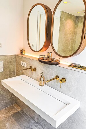 A bathroom with a white sink, two gold faucets, and two large mirrors with a wooden frame. - Luxus Neubau by Interhome (Munich)