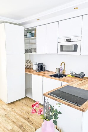 A modern kitchen with white cabinets, a wooden countertop, a built-in oven, and a sink. - Luxus Neubau by Interhome (Munich)
