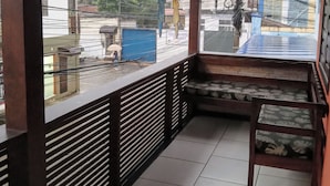 Un balcón cubierto con vistas a la calle, una banca y piso de baldosas.