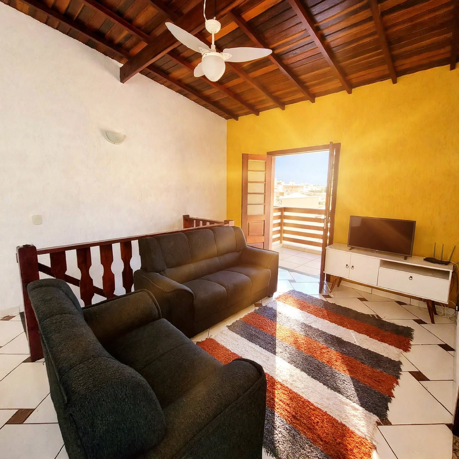 A living room with a sofa, a television, and a patterned rug.