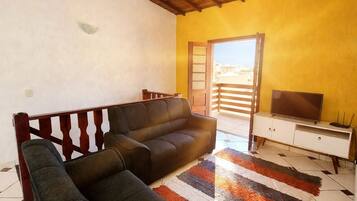 A living room with a sofa, a television, and a patterned rug.