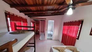 Una habitación con literas, techo de madera y cortinas rojas.