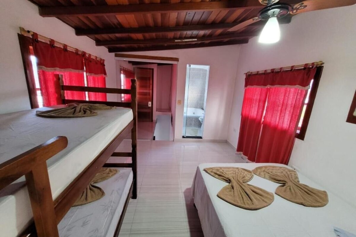 Een kamer met stapelbedden, een houten plafond en rode gordijnen.