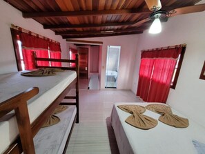 Een kamer met stapelbedden, een houten plafond en rode gordijnen.