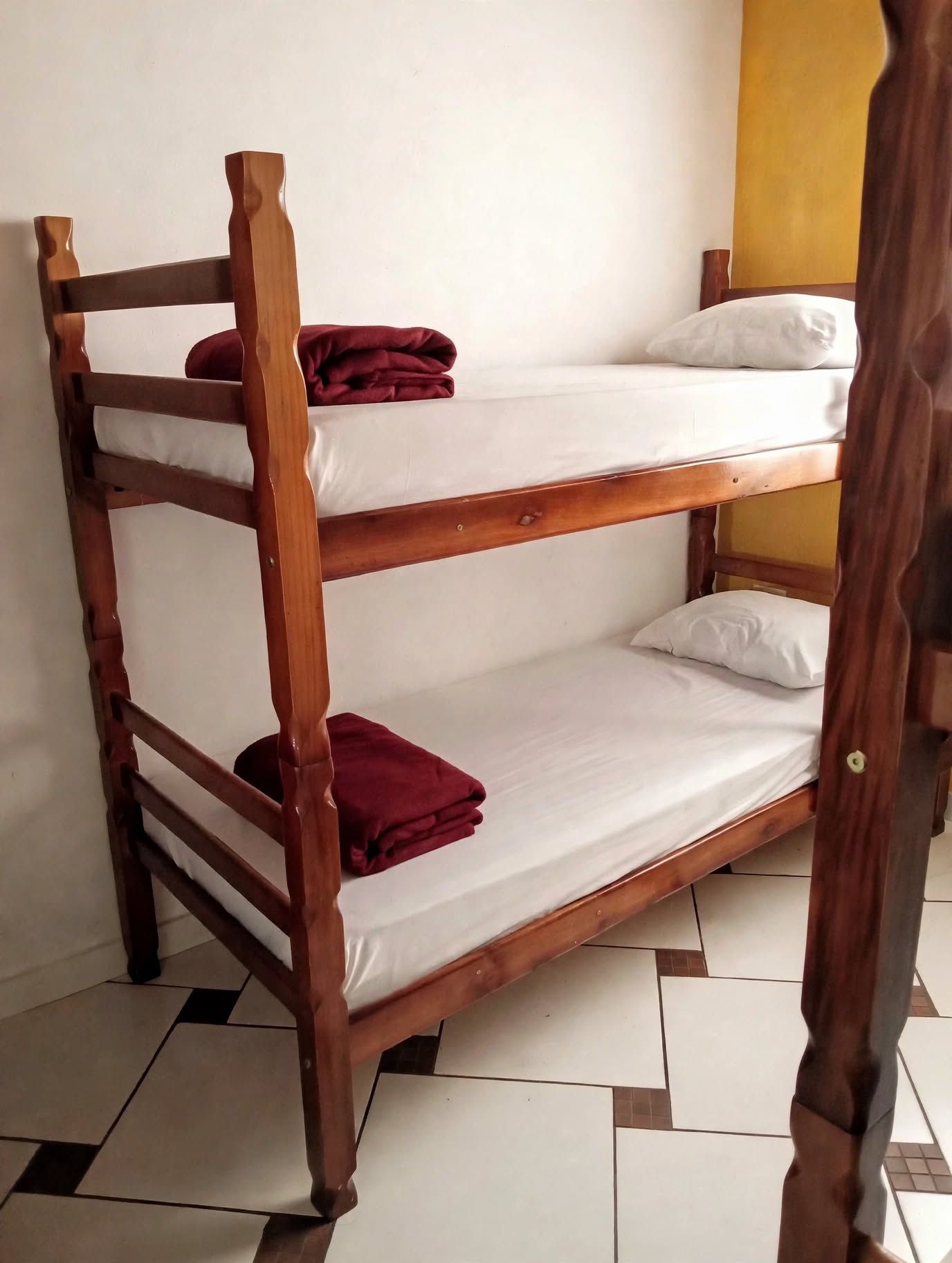 Una cama litera con dos niveles, cada uno con una almohada y un edredón doblado.