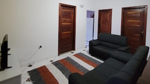 Una sala de estar con un sofá, puertas de madera y un ventilador de techo.