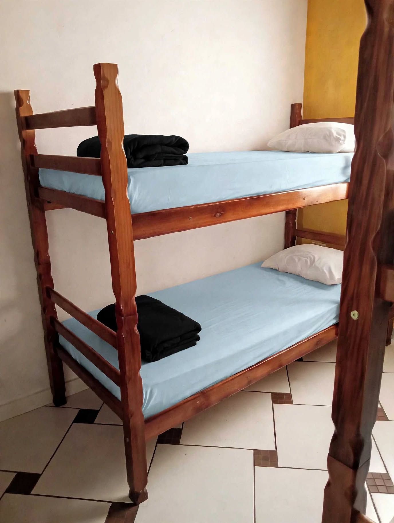 Ein Etagenbett mit zwei Schlafstellen, jeweils mit Kissen und einer zusammengelegten Decke.