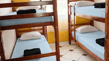 A room with bunk beds, a window with curtains, and a tiled floor.