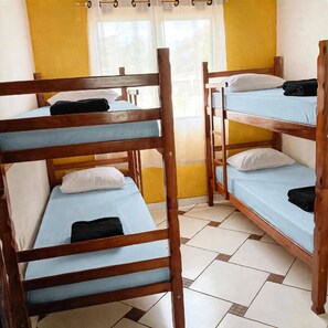 Una habitación con literas, una ventana con cortinas y piso de baldosas.