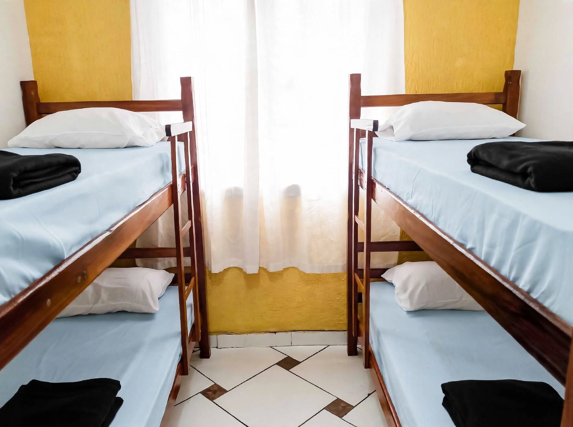 A room with two bunk beds, each with a pillow and a blanket.