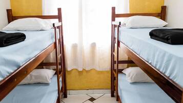 A room with two bunk beds, each with a pillow and a blanket.