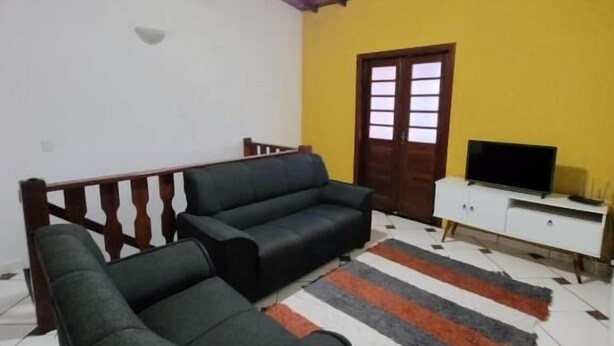 Una sala de estar con un conjunto de sofá, una televisión y un ventilador de techo.