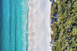 Vista aérea de una playa con aguas turquesas cristalinas y una orilla arenosa.