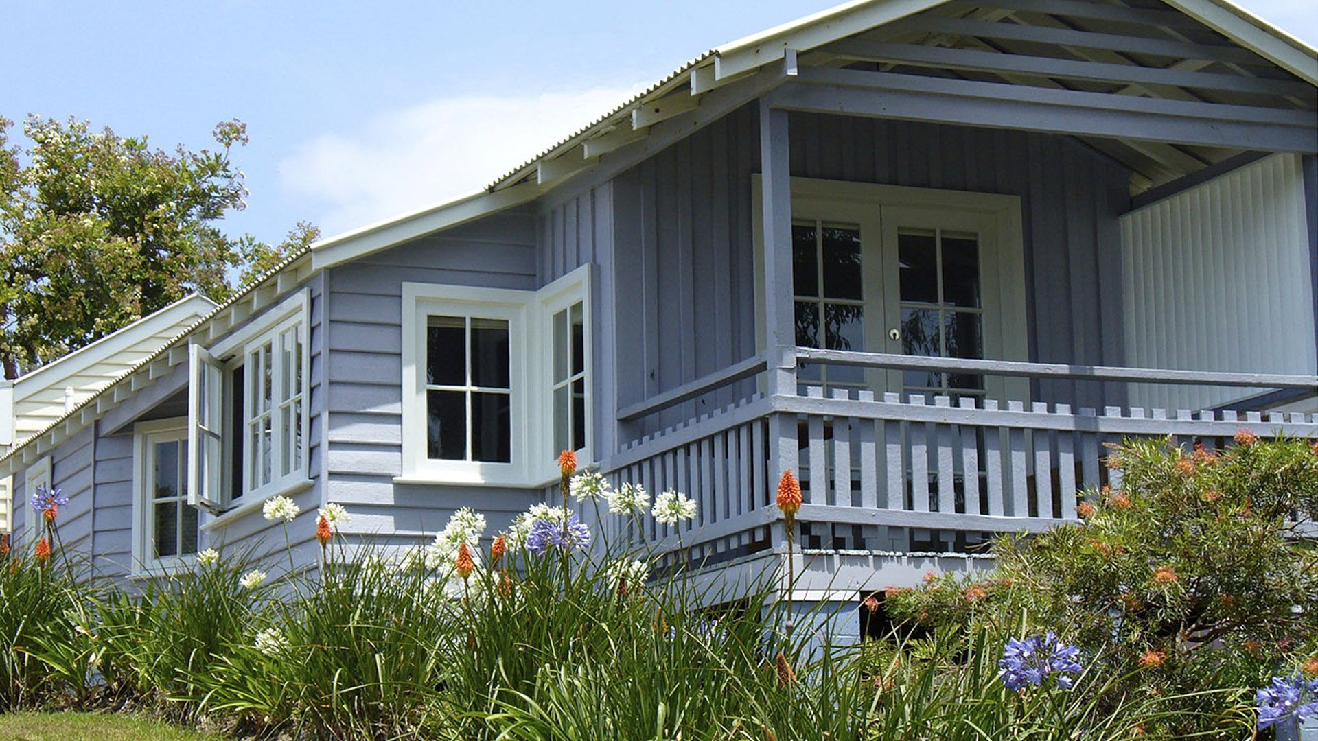 A two-story house with a porch, white-framed windows, and a grey siding exterior.
