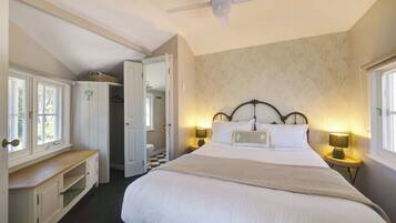 A bedroom with a bed, bedside lamps, a ceiling fan, and a window.