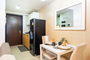 Une cuisine de taille réduite, équipée d’un réfrigérateur, d’un four à micro-ondes et de meubles de rangement en bois.