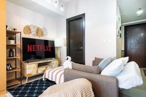 Un salon moderne avec un téléviseur à écran plat, un canapé, une table basse et une bibliothèque.