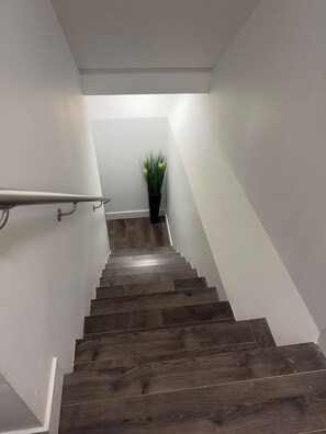 A wooden staircase with a handrail, leading to a landing with a potted plant. - South Surrey Suite! 
Close to recreation, Morgan crossing, white rock beach! (Surrey)