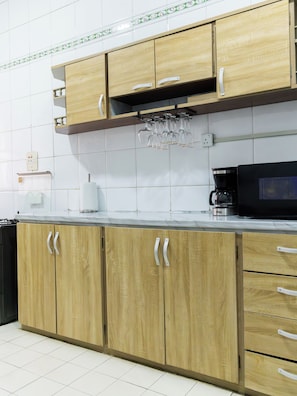 Cozinha com armários de madeira, bancada, cafeteira e micro-ondas.