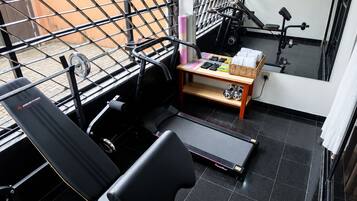 Et fitnessrum med træningsudstyr, en bænk og et fjernsyn ophængt på væggen.