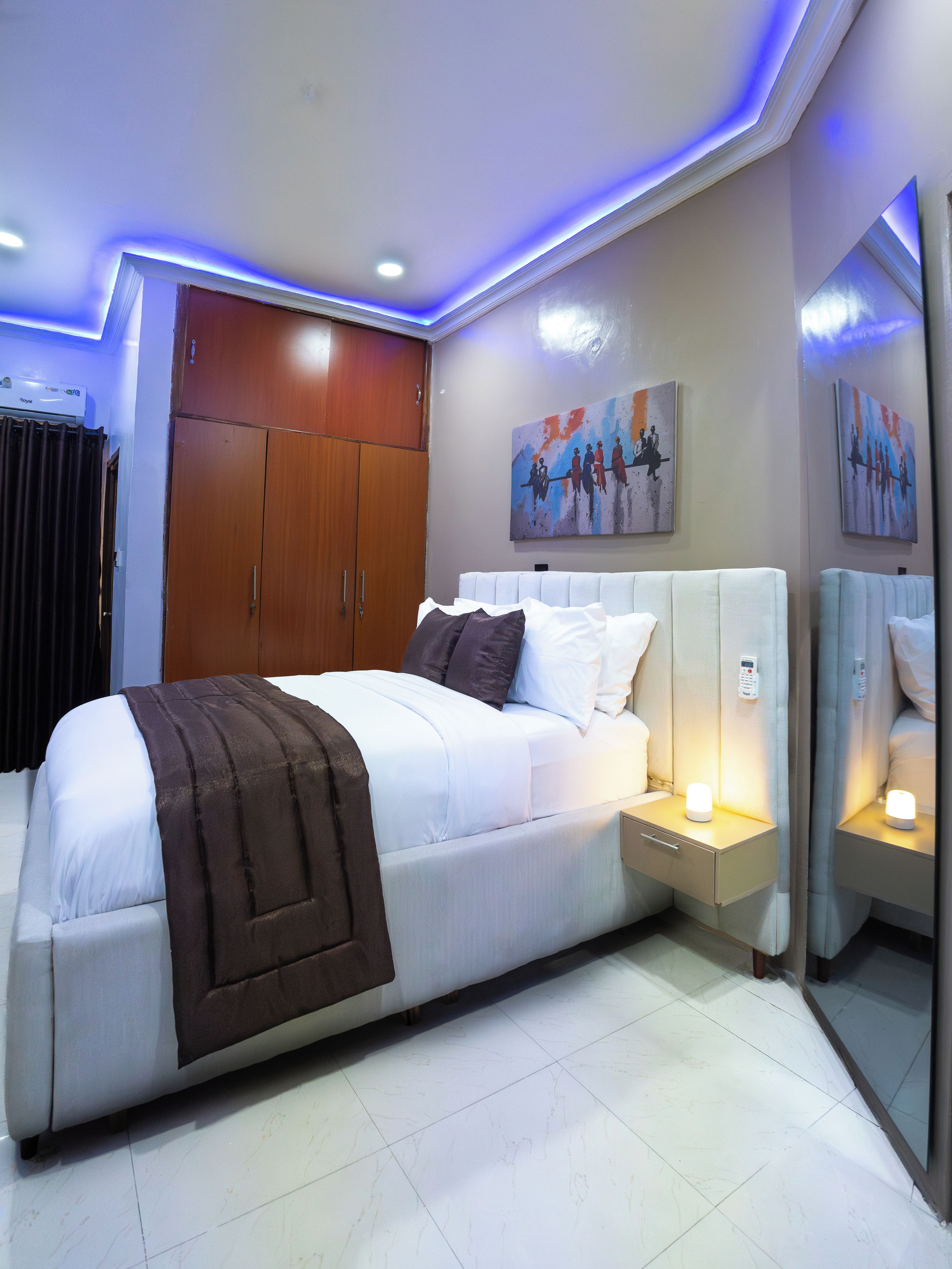 Un dormitorio moderno con una cama grande, lámparas de noche, un armario y obras de arte en las paredes.