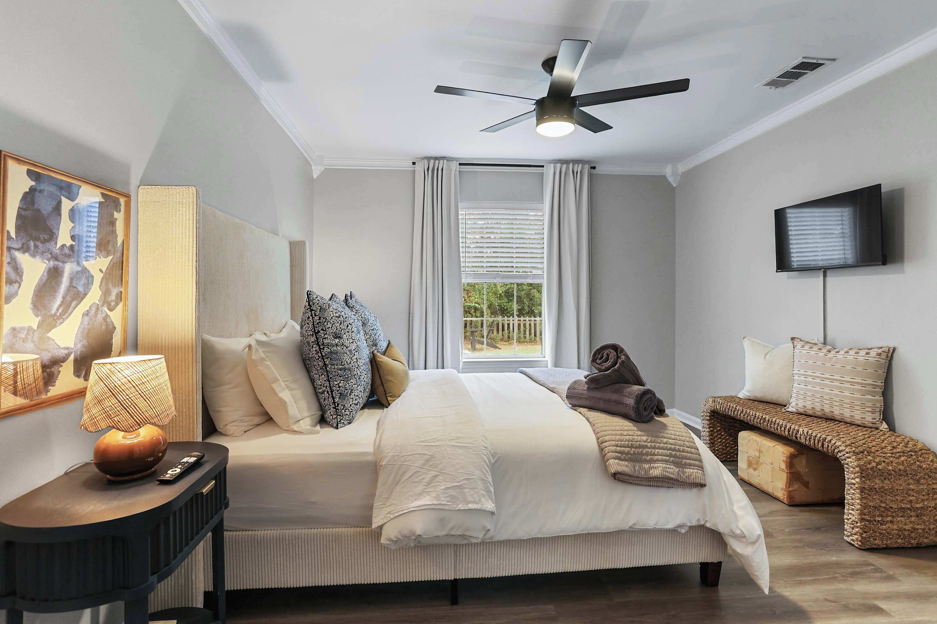 Une chambre à coucher avec un lit, une table de chevet, une lampe et un téléviseur fixé au mur.