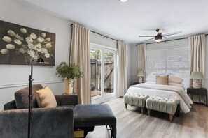 Een slaapkamer met een bed, een bureau, een stoel, een vloerlamp en een raam met gordijnen.
