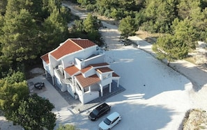 A two-story building with a red-tiled roof, surrounded by trees, and a gravel driveway with two cars parked. - Two bedroom apartment with terrace and sea view Pridraga - Cuskijaš, Novigrad (A-27969-a) (Pridraga)