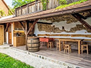 Ein rustikaler Essbereich im Freien mit einer Steinmauer, Holzmöbeln und einem Fass.