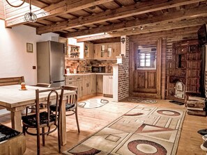 A rustic kitchen with wooden cabinets, a dining table, and a patterned rug. - Casa Rico by Interhome (Vale)