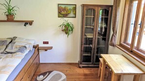 Una habitación con cama, una mesa, un armario y una ventana.