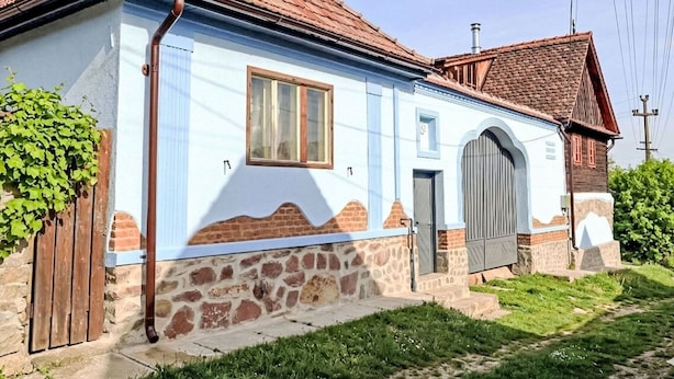 Una casa de un piso con techo inclinado, puerta principal y un pequeño porche.